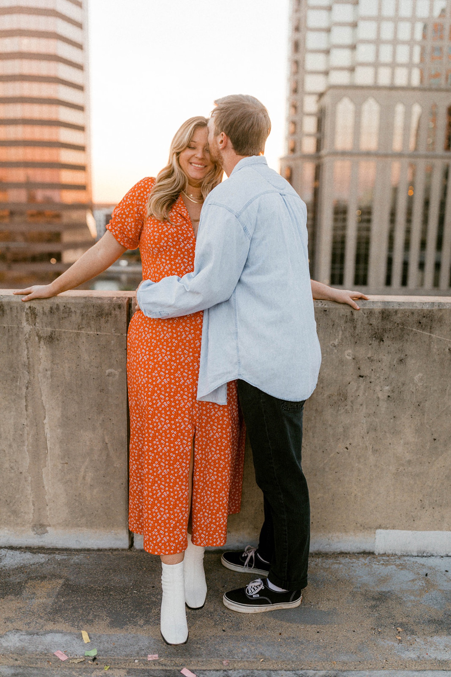 couple kissing on parking garage rooftop with sunset in background