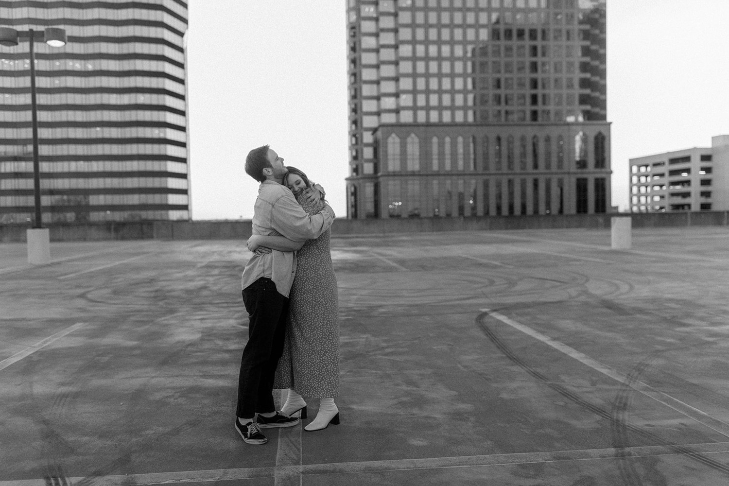 couple hugging on parking garage rooftop black and white