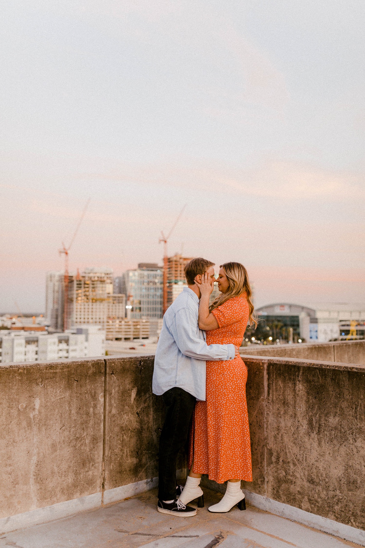 couple kissing with downtown tampa in background at sunset dreamy engagement session