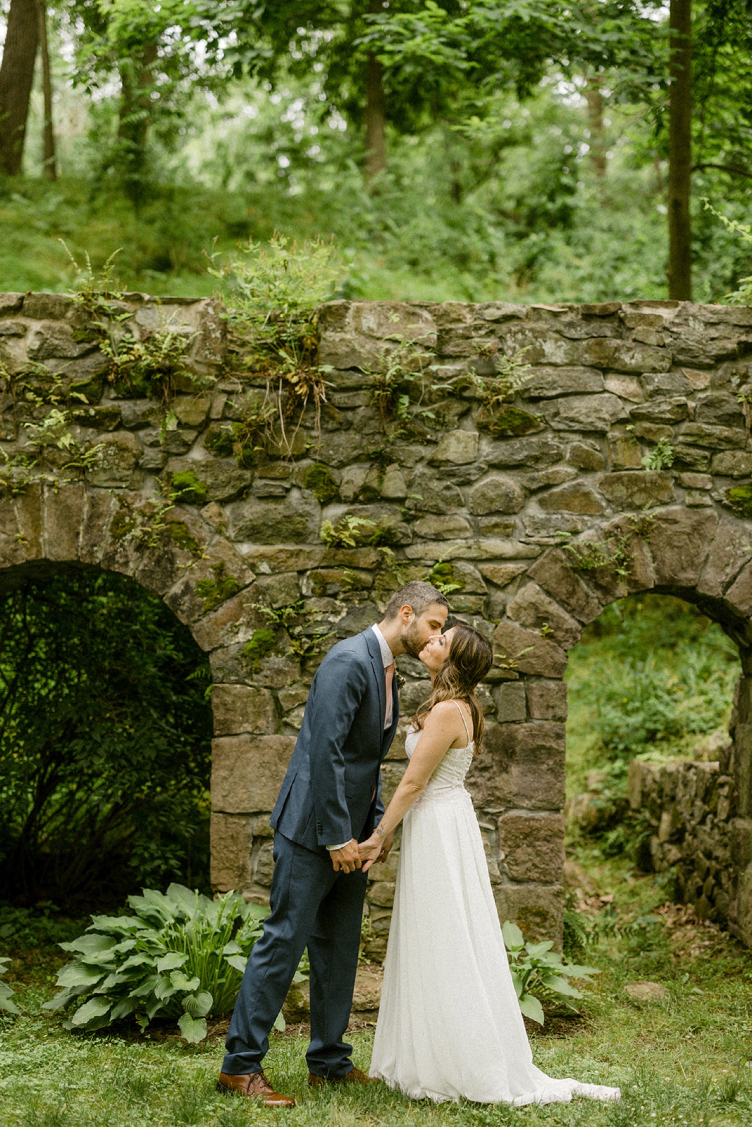 couple kissing in front of stone arches moonstone manor wedding session