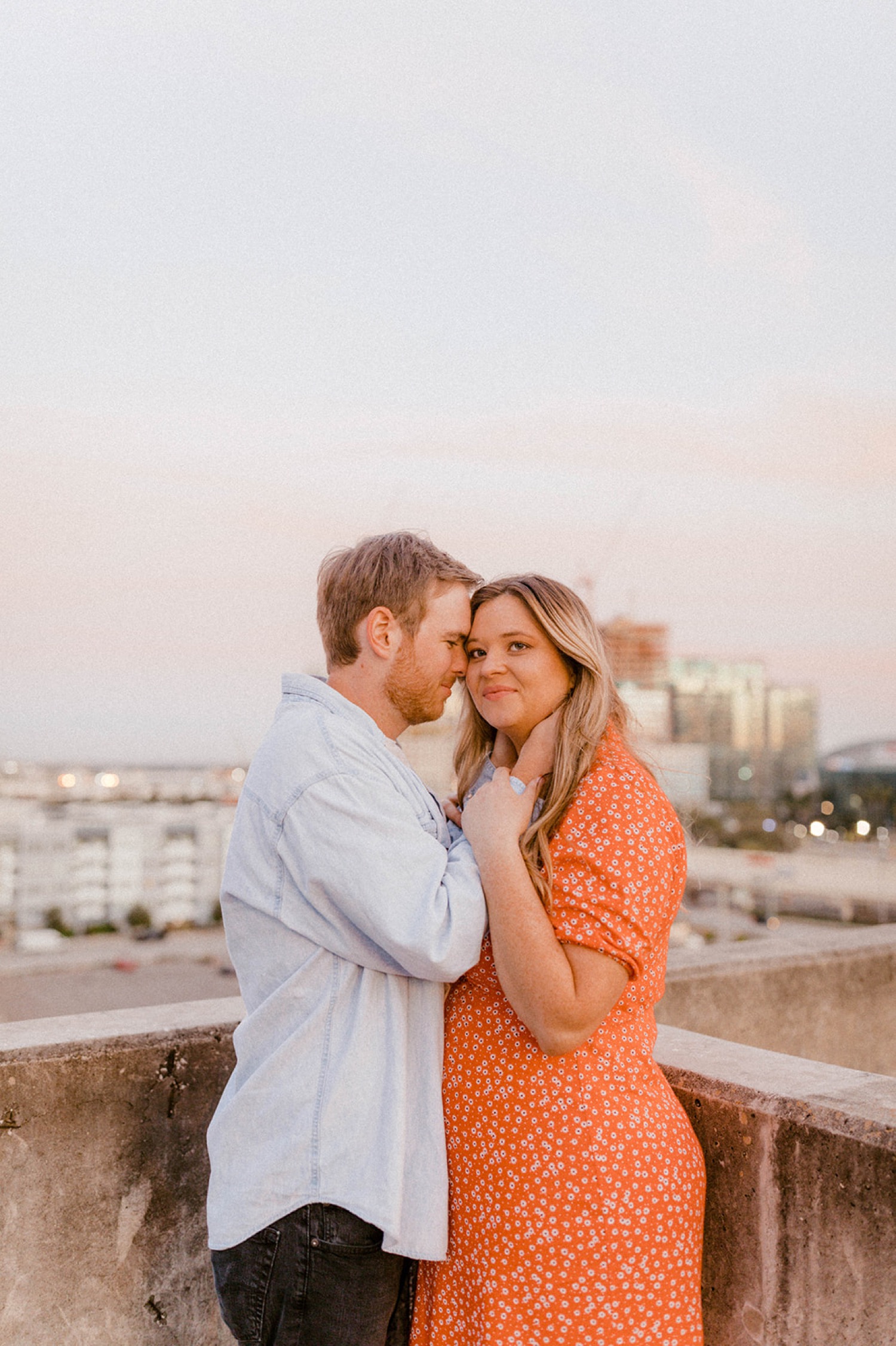 couple holding each other looking at camera during sunset dreamy engagement session