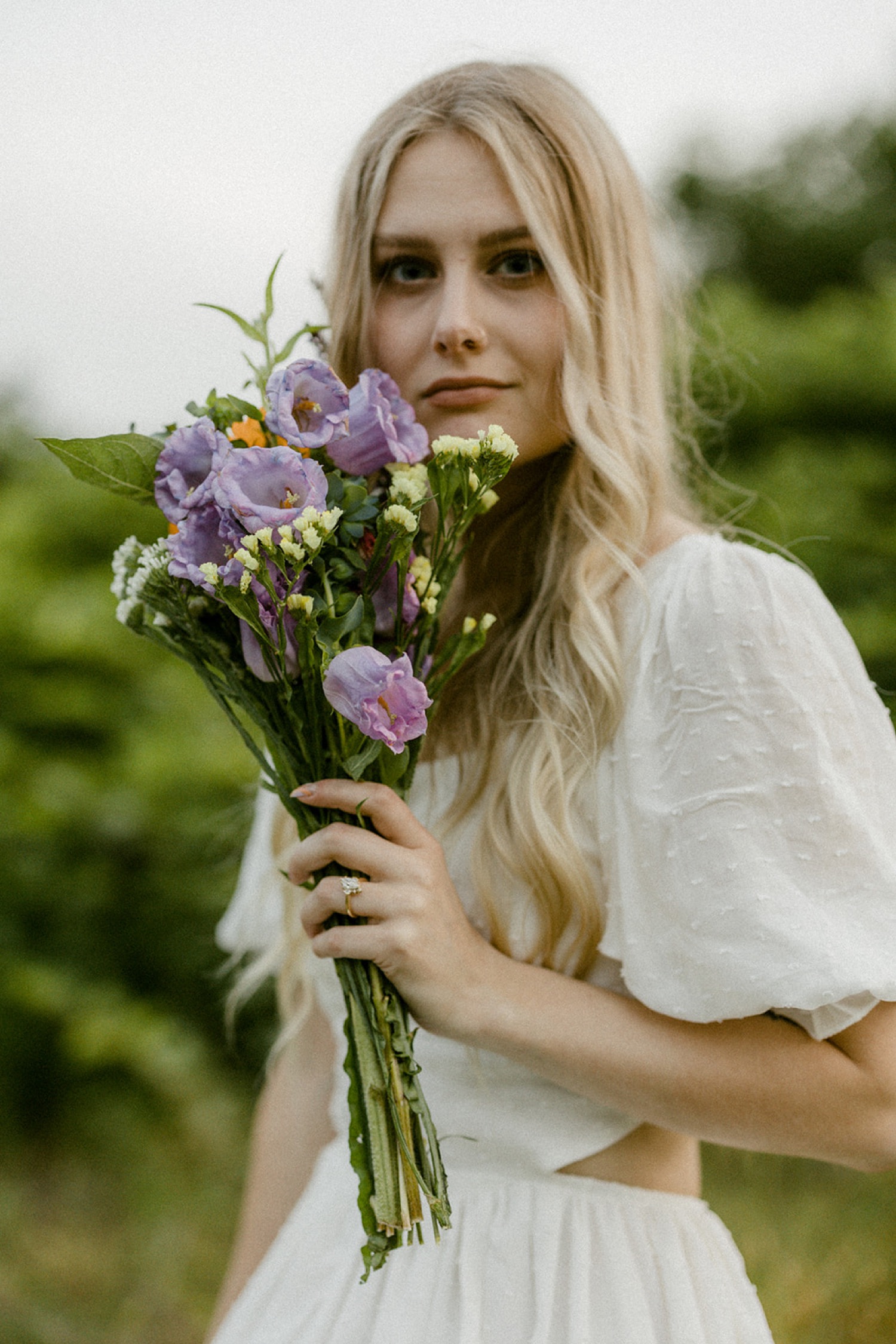 girl in white dress holding purple flowers boho chic