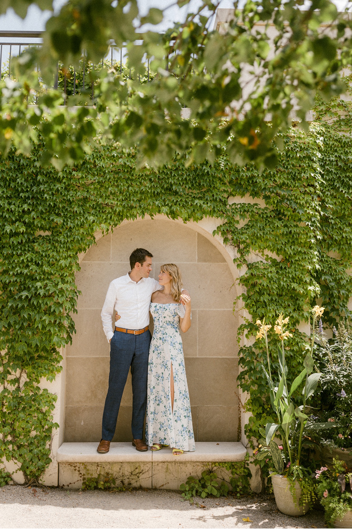 couple standing under arch arm around shoulder vine wall at longwood gardens