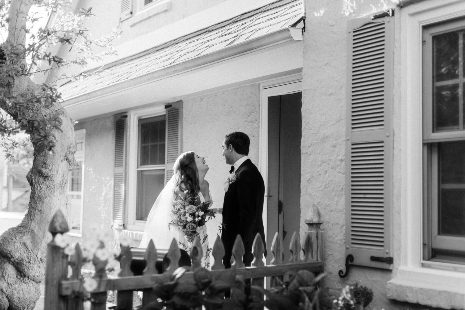 couple laughing outside of house on wedding day