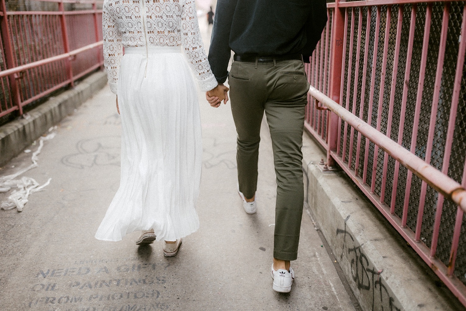 couple holding hands walking from behind