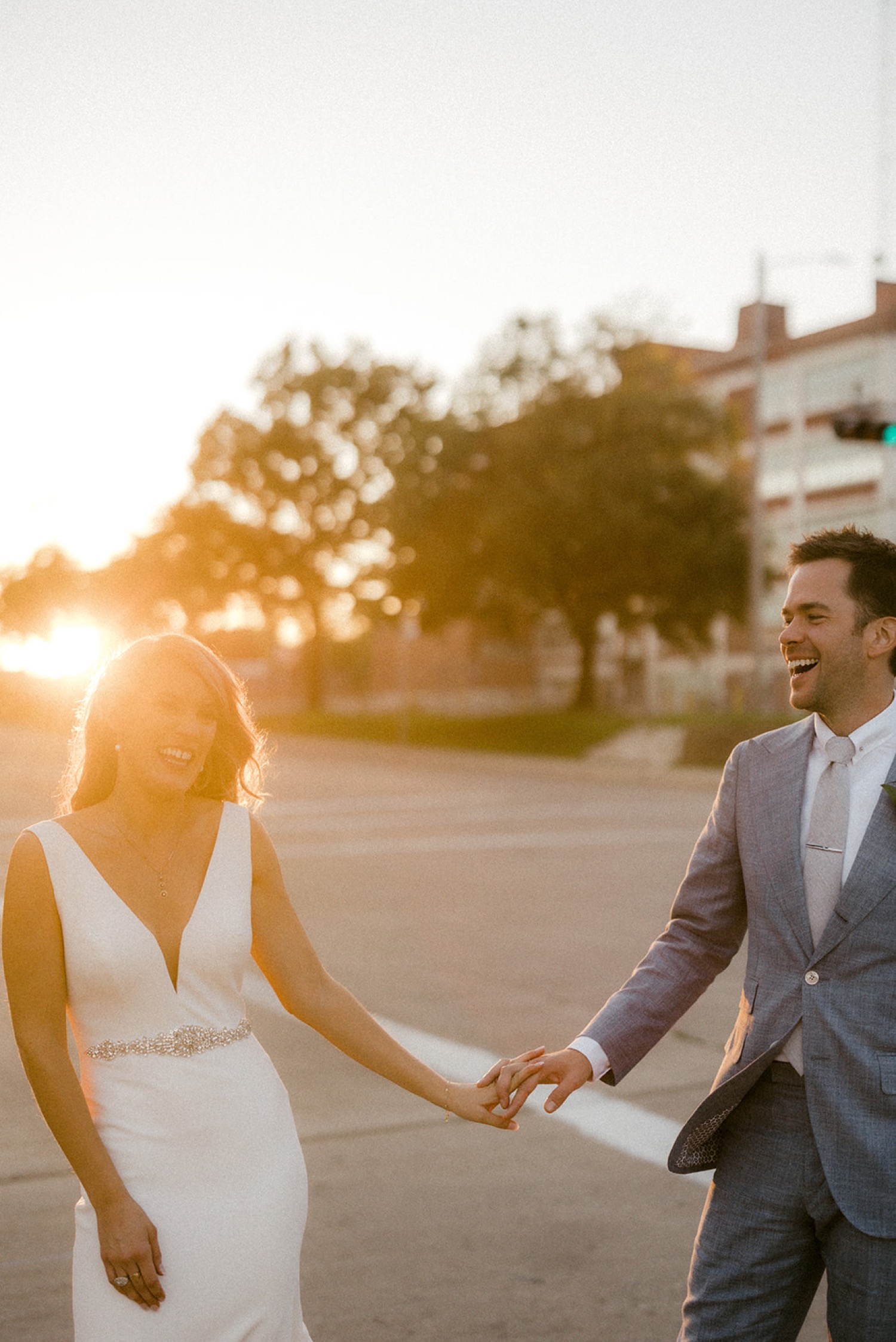 couple holding hands laughing golden hour wedding portrait
