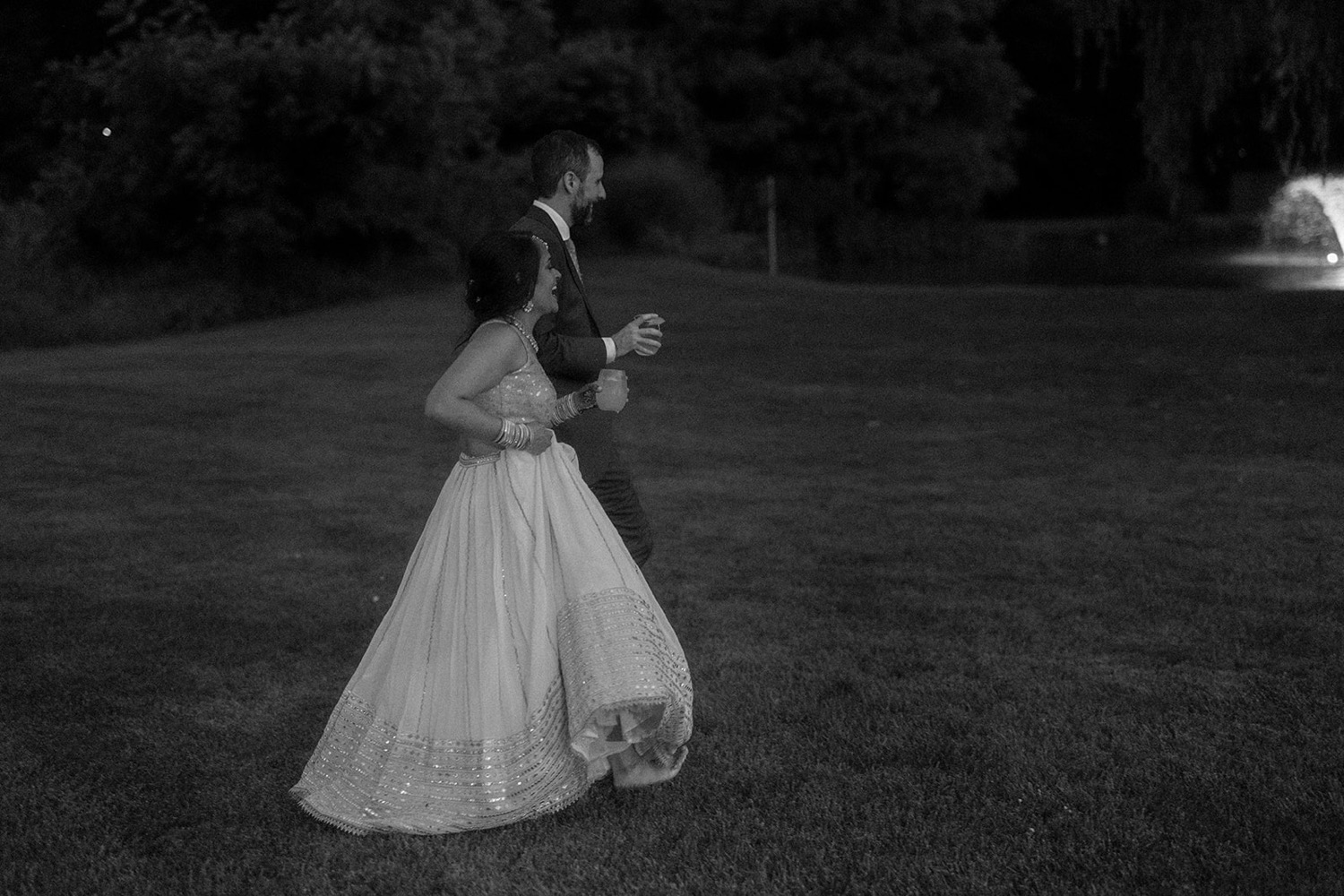 bride and groom walking outside at night wedding reception