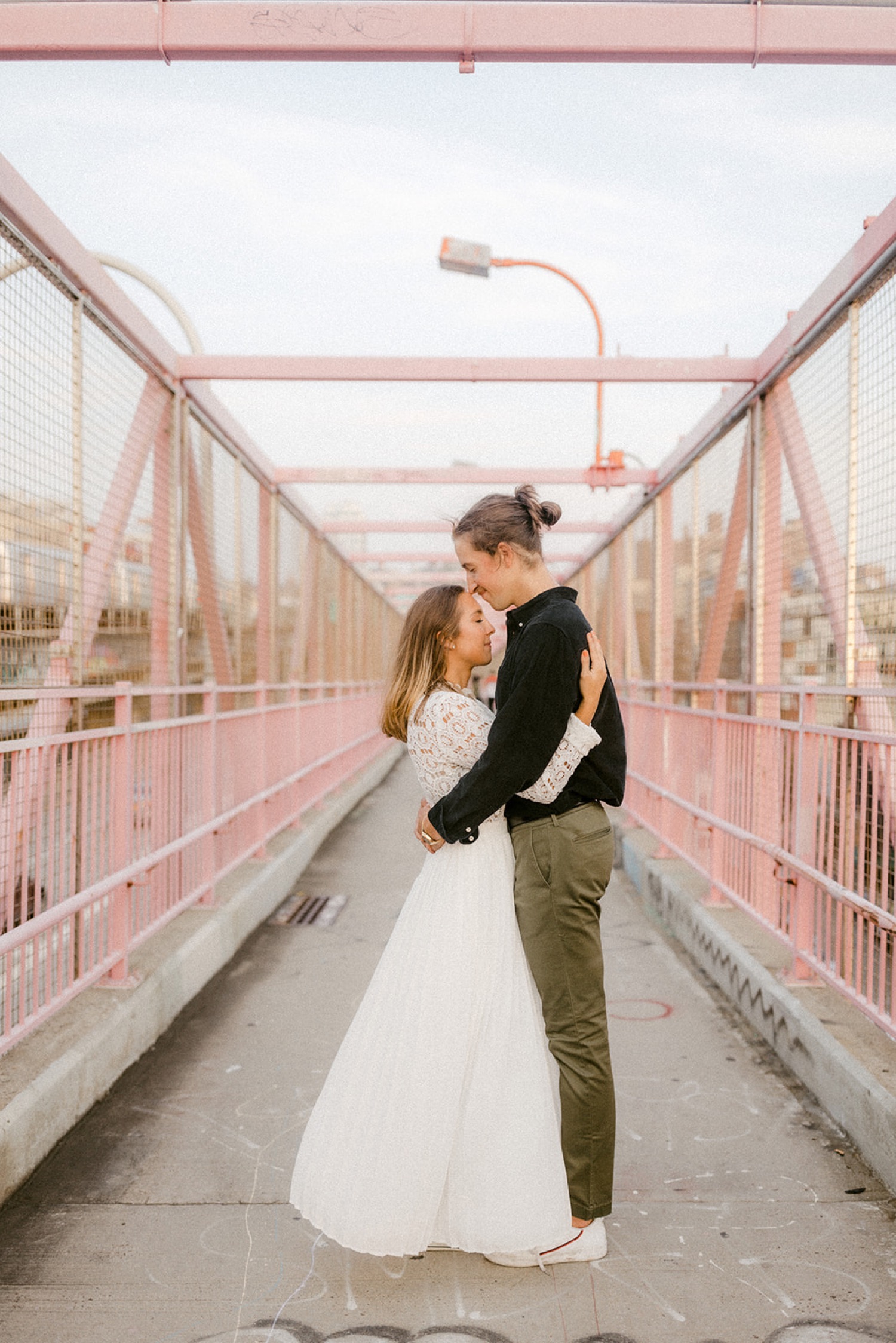 couple embracing on pink bridge brooklyn engagement session