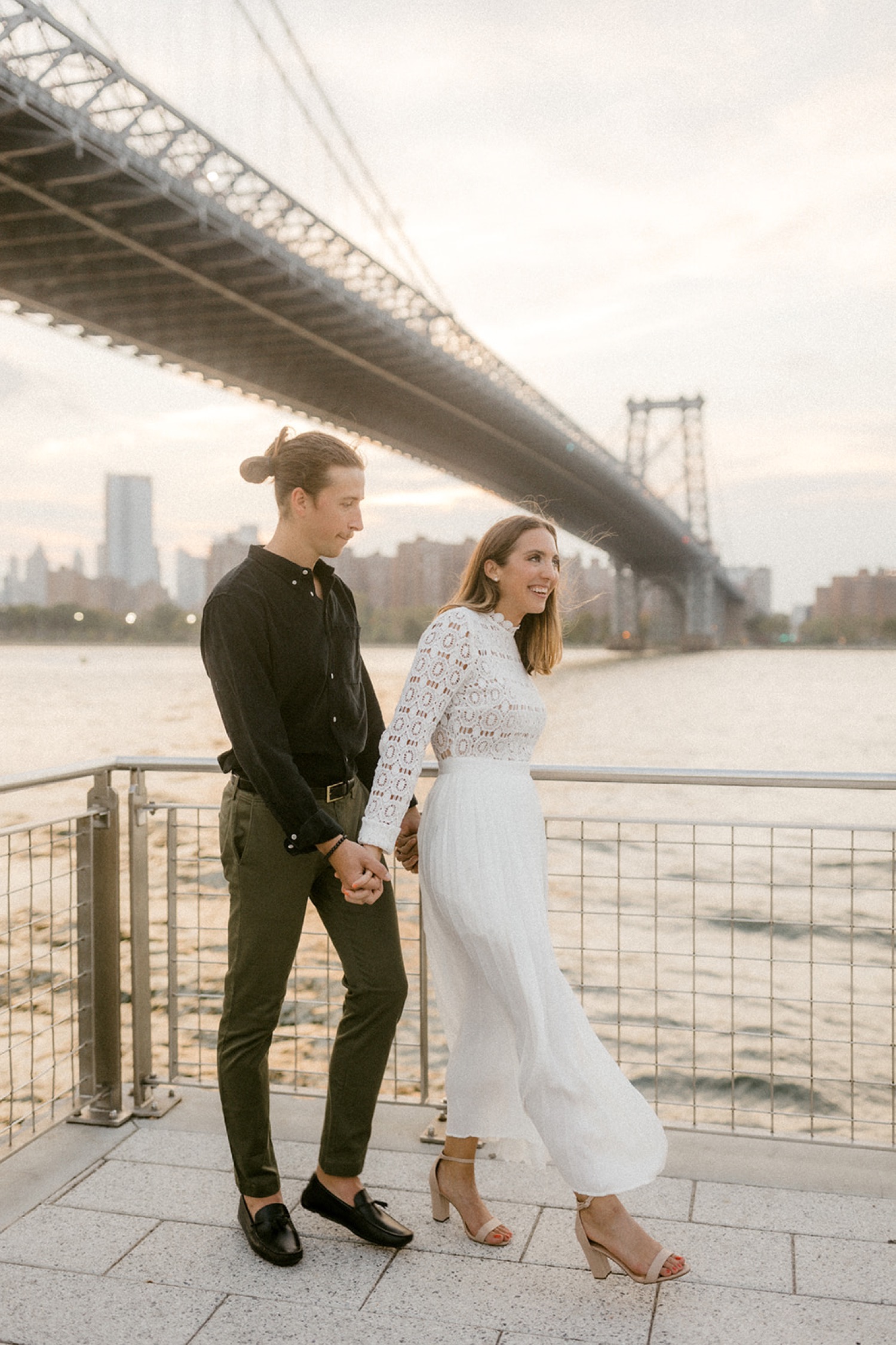 couple walking under brooklyn bridge