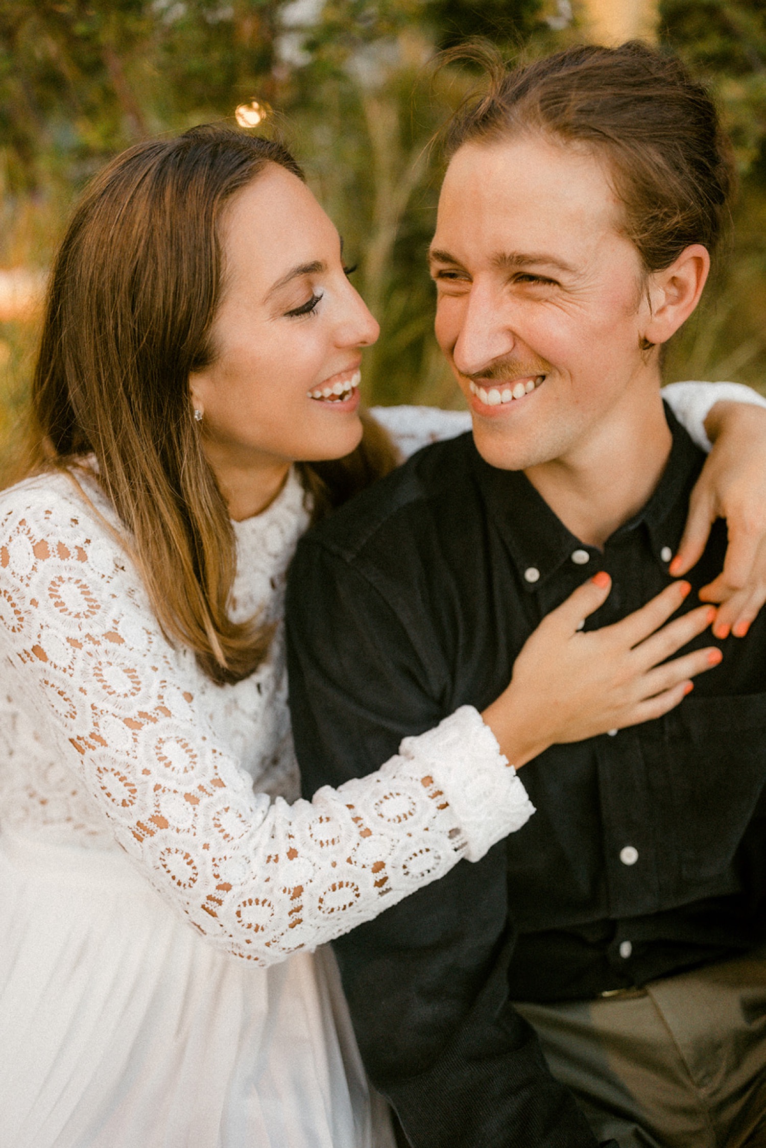 couple sitting on bench laughing engagement session