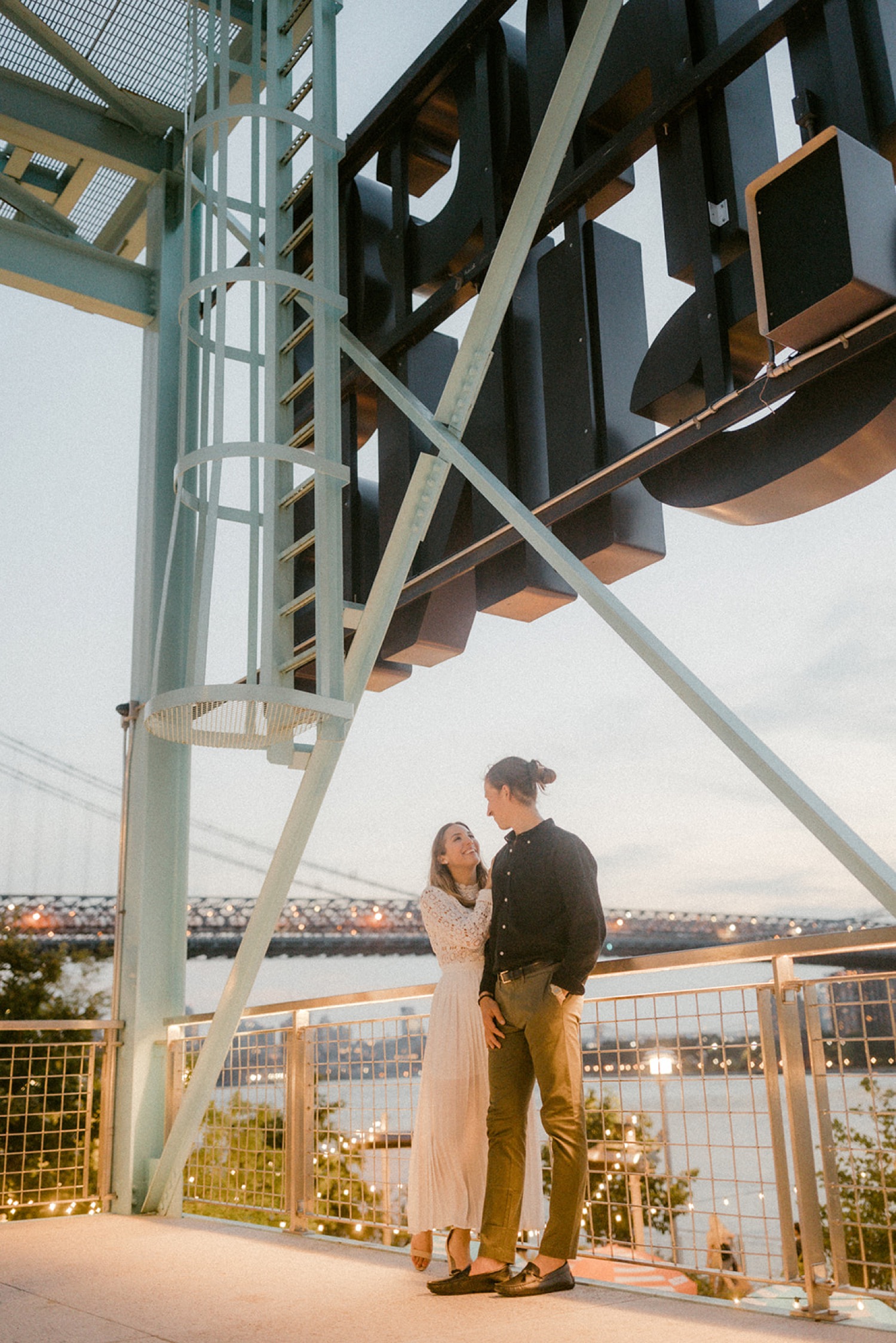 couple standing behind sign brooklyn engagement session